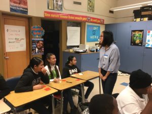 A KTGY staff volunteer talks to students at Madison Park Middle School in Oakland CA